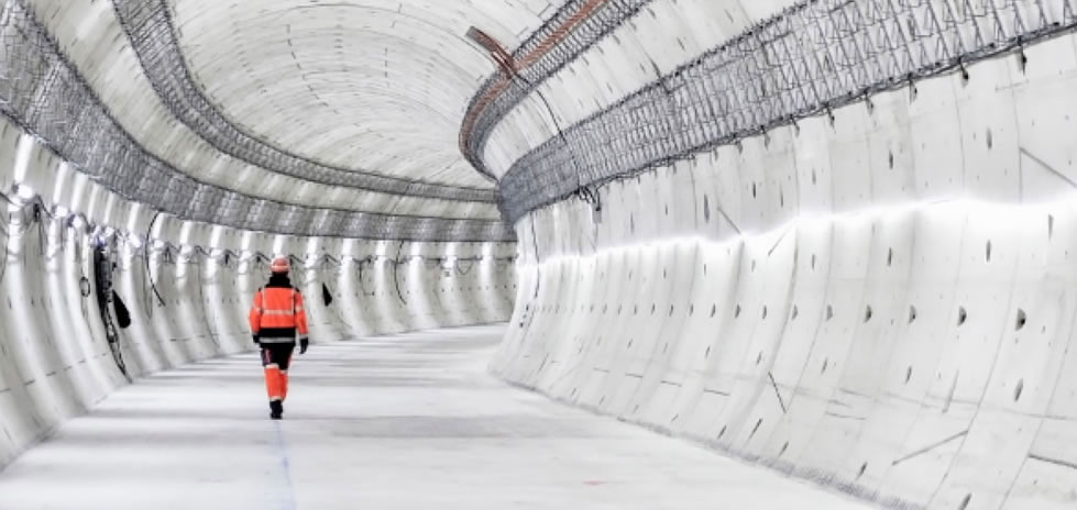 Hombre con casco naranja caminando por un largo túnel