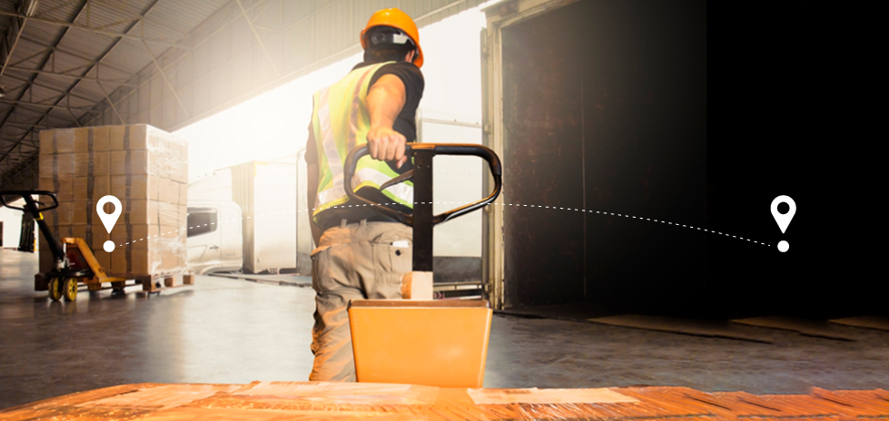 A man in an orange hardhat pulling a pallet in warehouse