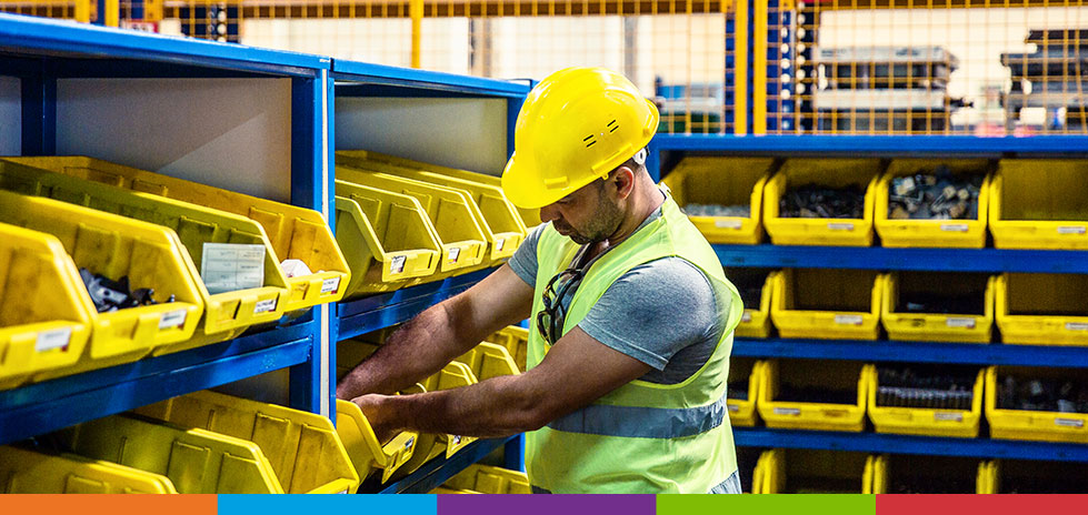 Man in a yellow hard hat pulling fasteners out of a yellow bin managing his inventory