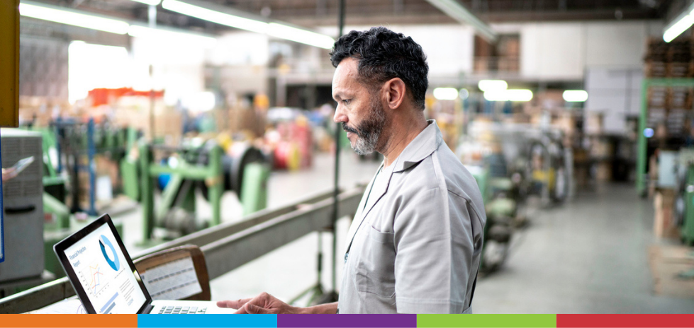 A man standing in a manufacturing facility looking at a laptop of VMI solutions