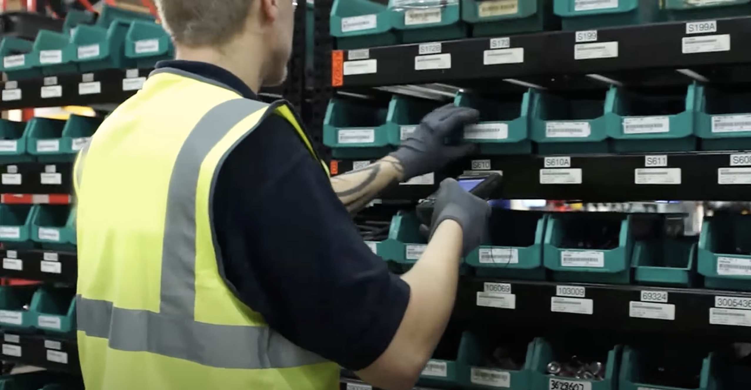 Man looking through bins of fasteners with a barcode scanner